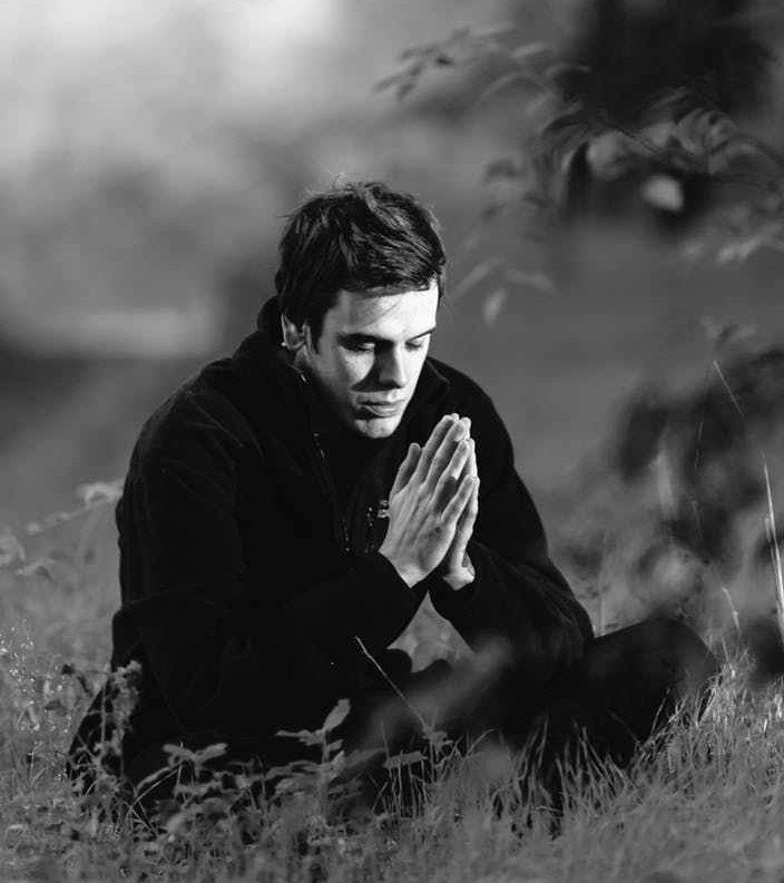 grayscale photography of man sitting on grass field