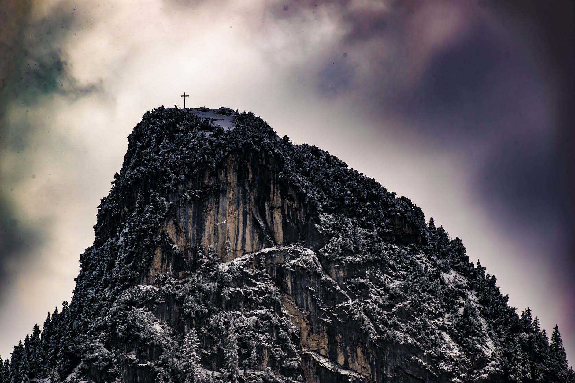 low angle photography of cross on top of mountain