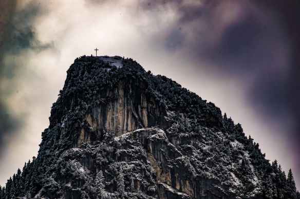 low angle photography of cross on top of mountain