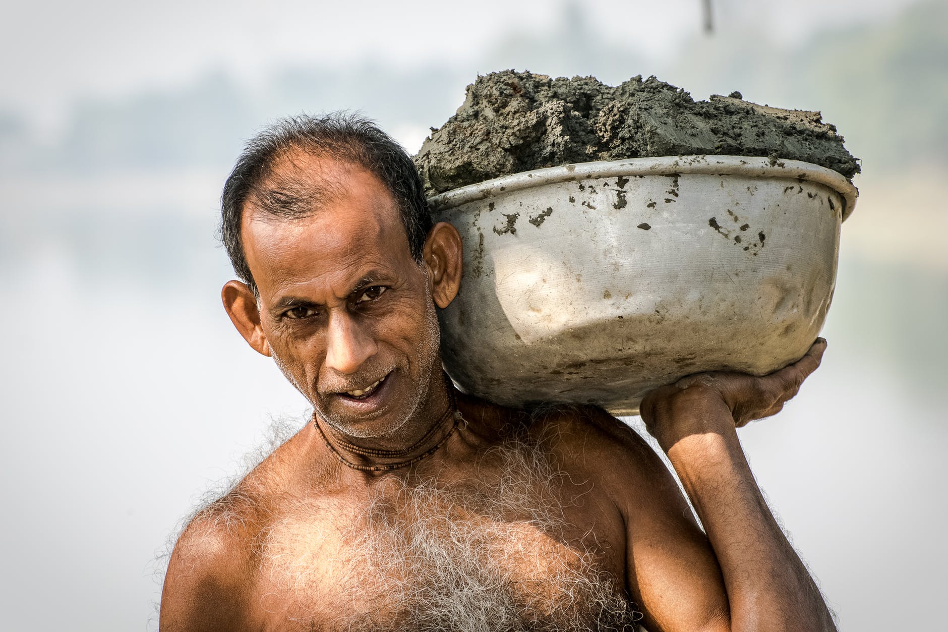 man carrying bucket of mud