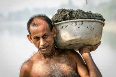 man carrying bucket of mud