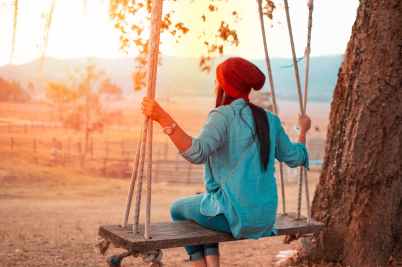 woman sitting on swing beside tree