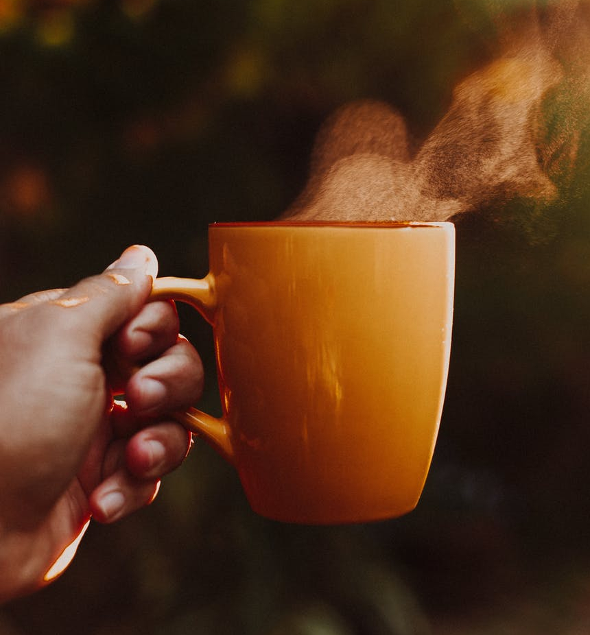 photo of a hand holding out a steaming cup