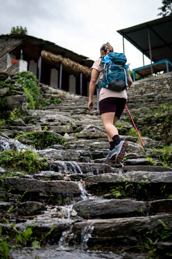 woman carrying black and blue backpack walking on rocky stairs