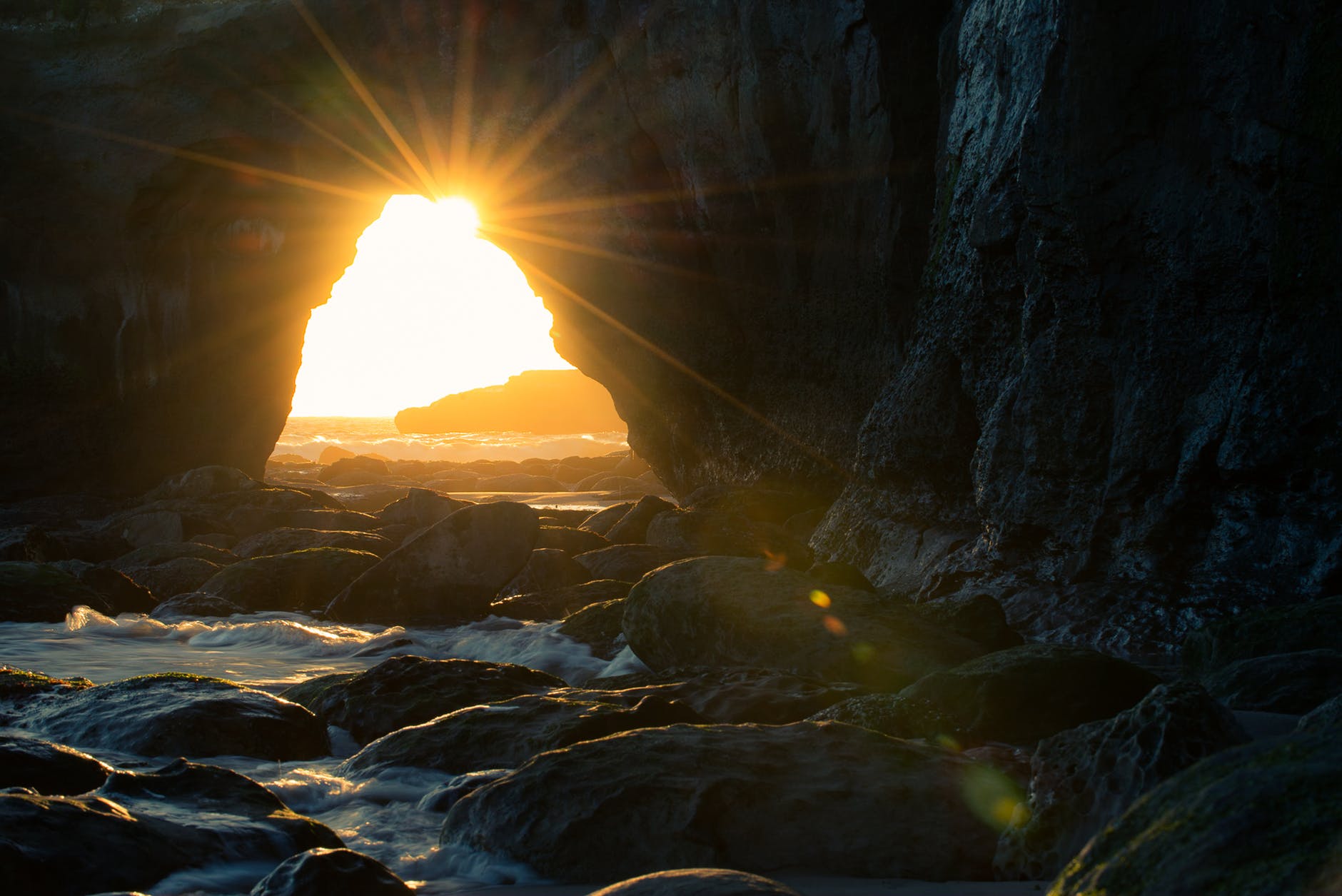 cave near body of water at sunset