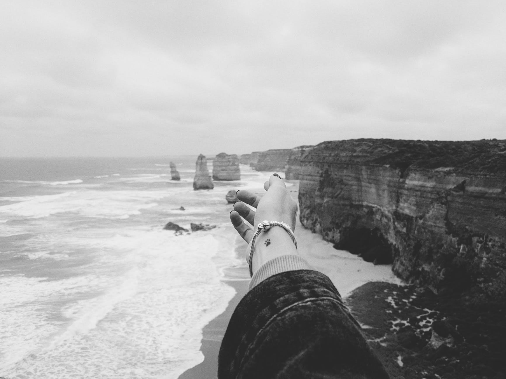 greyscale photograph of person standing near the ocean