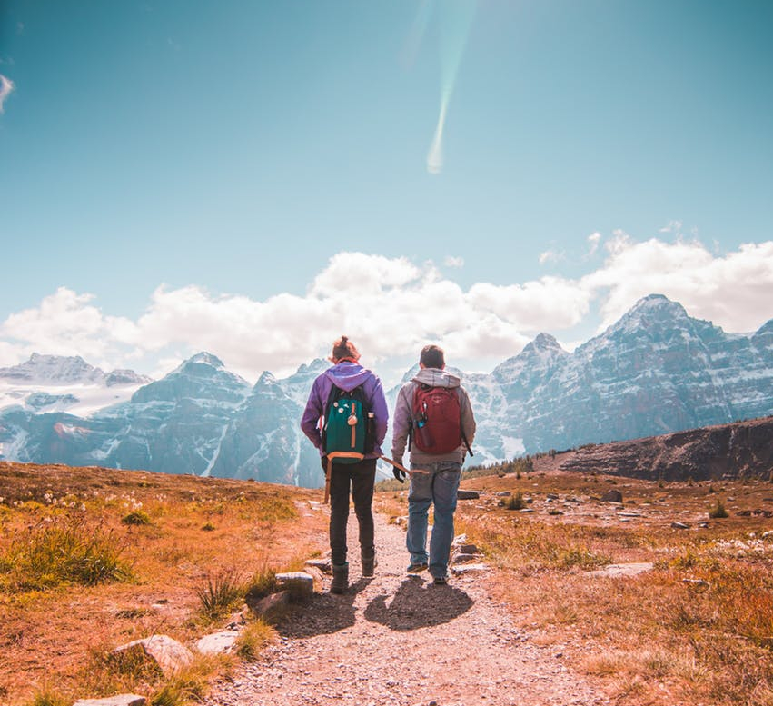 two person walking on unpaved road