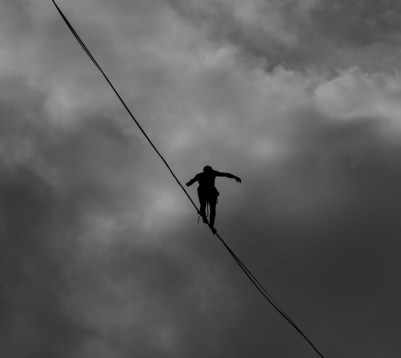 low angle photo grayscale of person tightrope walking