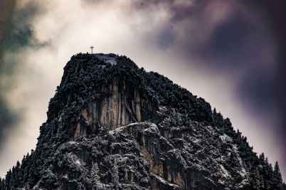 low angle photography of cross on top of mountain