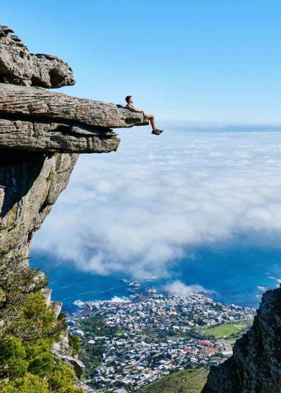 person sitting on mountain cliff