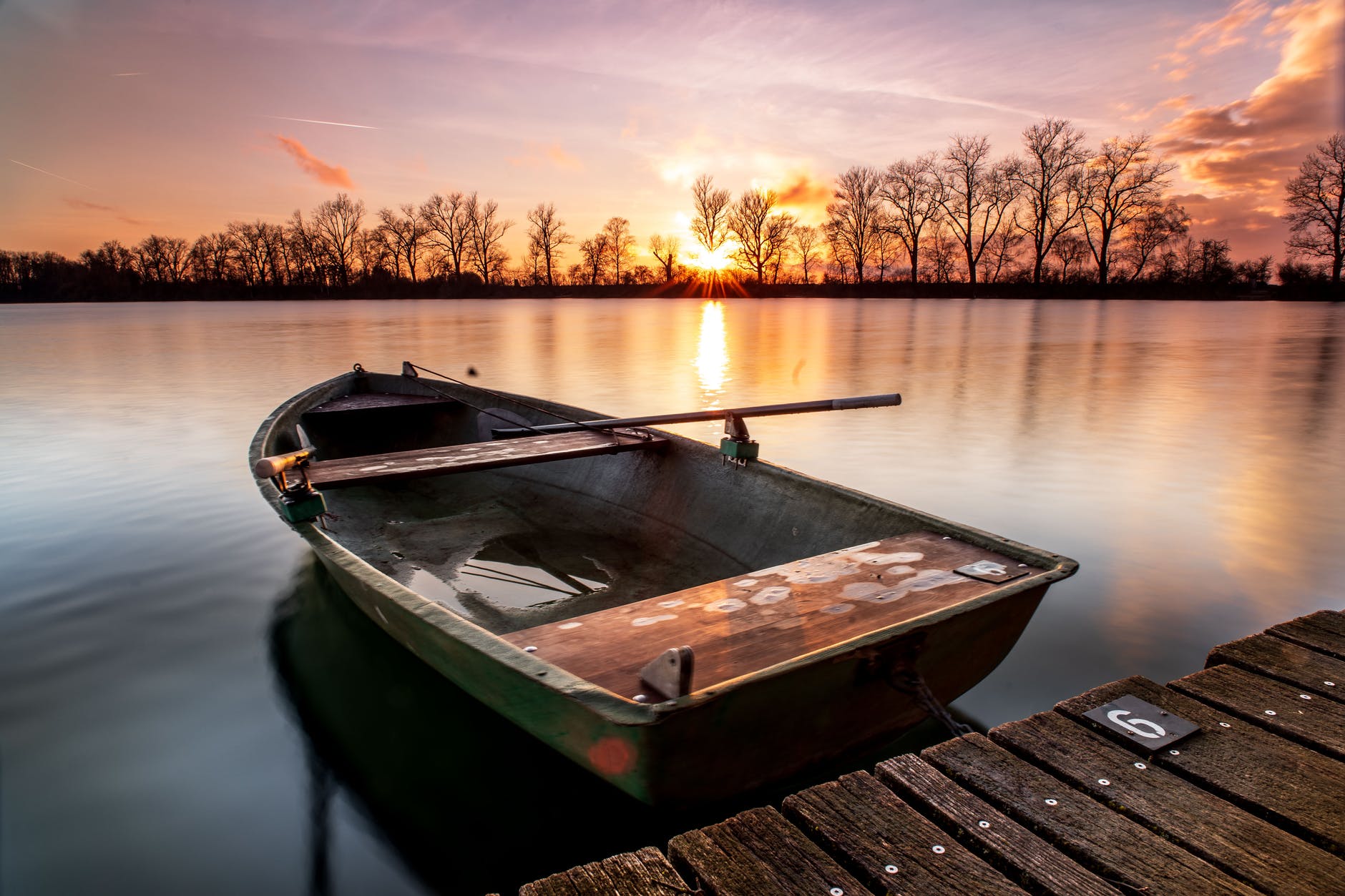 brown wooden boat on dock during sunset