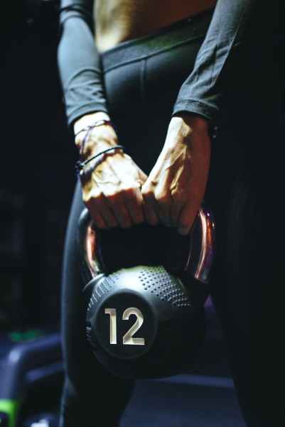 crop sportswoman doing exercise with kettlebell in gym